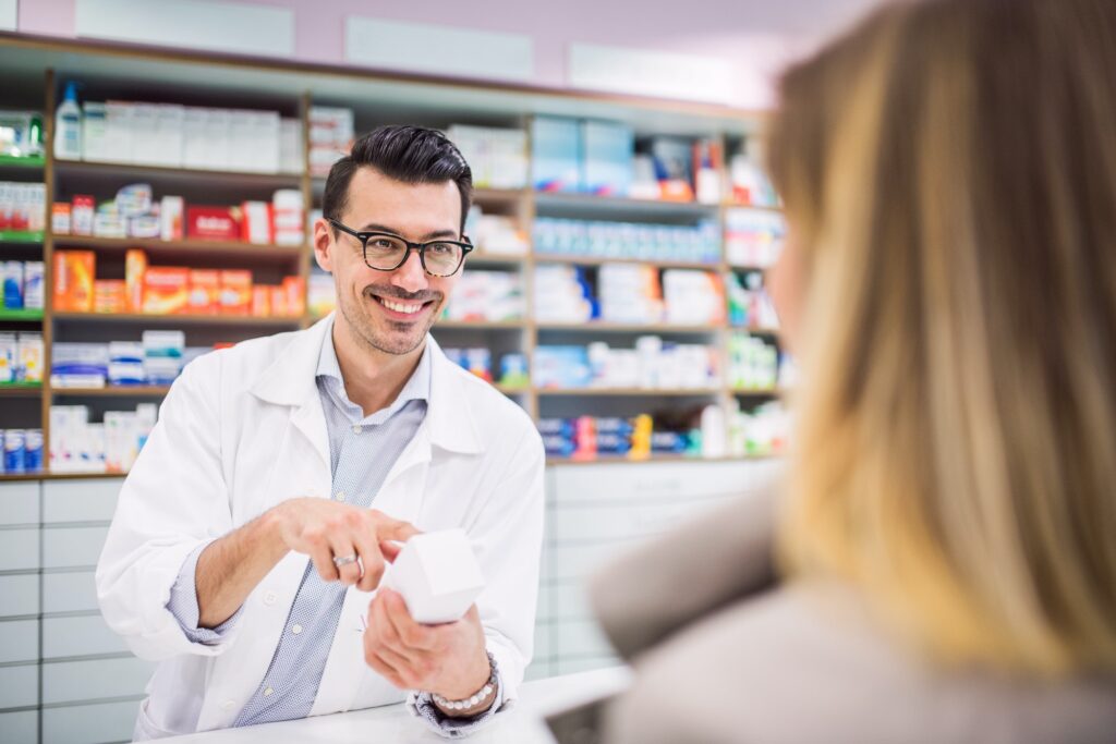 Male pharmacist serving a female customer.