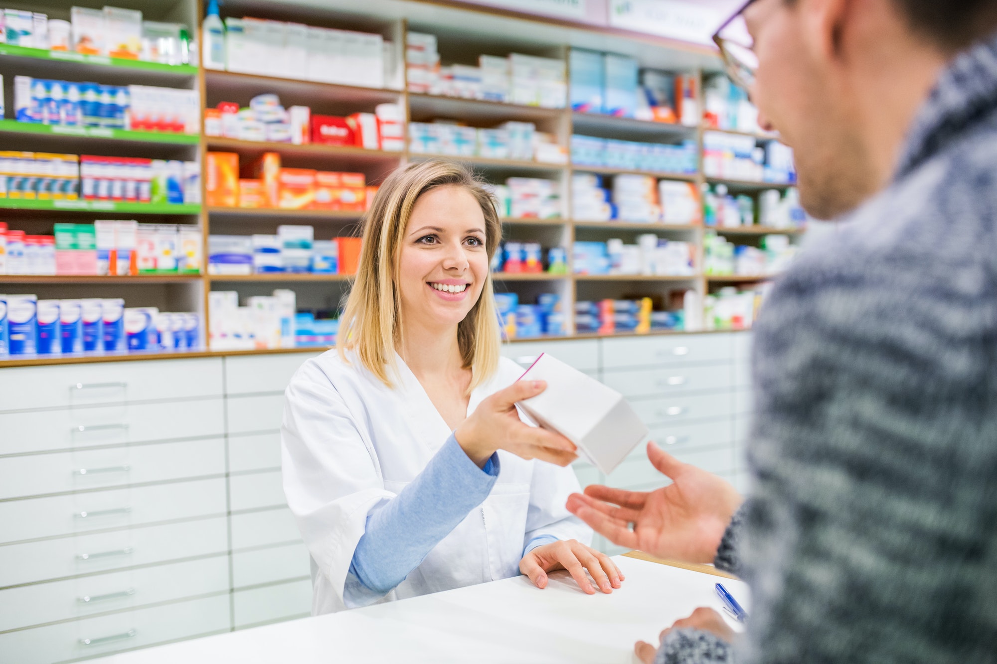 Female pharmacist serving a male customer.